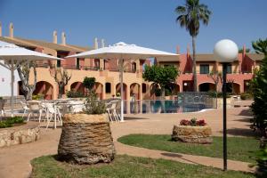 un complejo con mesas, sombrillas y una piscina en Grupoandria Aparthotel Club Andria, en Cala Santandria