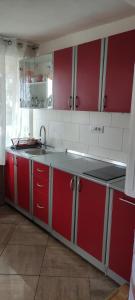a kitchen with red cabinets and a sink at Apartments Aleksandra in Crikvenica