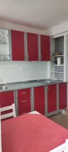 a kitchen with red and white cabinets and a red table at Apartments Aleksandra in Crikvenica