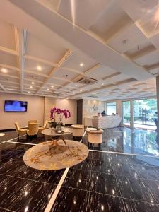 een lobby met een kamer met een bank en tafels en stoelen bij Hotel Aman Kuala Lumpur in Kuala Lumpur