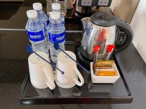 a tray with bottles of water and a tea kettle at The Straits Hotel & Suites in Melaka