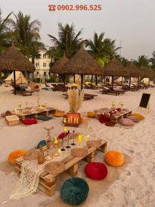 a beach with tables and straw umbrellas on the sand at Vinhomes Grand Park Quận 9-Bống House in Long Bình