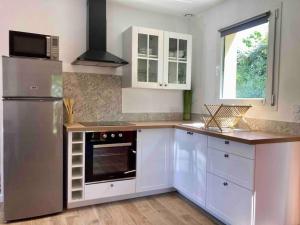 uma cozinha com armários brancos e um frigorífico de aço inoxidável em Maison neuve à deux pas du Mont em Beauvoir