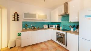 una cocina con armarios blancos y azulejos azules en El Buen Ocio Holiday Rental en Castellón de Rugat