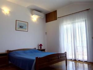 a bedroom with a blue bed and a large window at Apartments Ivanka in Starigrad