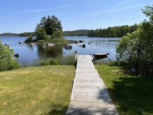 un chemin en bois menant à un lac avec un quai dans l'établissement Newly built cottage located on a lake plot by Lake Flaten, à Järnforsen