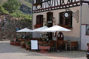 ein Restaurant mit Tischen und Sonnenschirmen vor einem Gebäude in der Unterkunft Hotel Weinhaus Weiler in Oberwesel