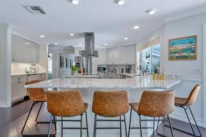a kitchen with a large white island with bar stools at Waterfront Oasis w/ Pool Minutes to Downtown! in Boynton Beach