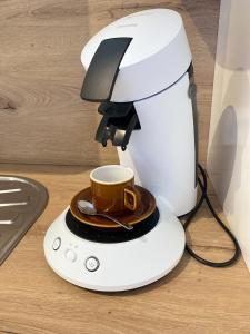 eine Kaffeemaschine mit einer Tasse darüber in der Unterkunft Appartement luxueux rénové avec balcon & garage in Troyes