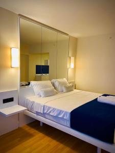 um quarto com uma grande cama branca e um grande espelho. em Lika's Apartment em Batumi