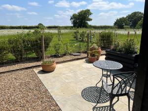 a patio with a table and chairs and a vineyard at The Retreat Field View in Great Maplestead