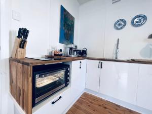 a kitchen with white cabinets and a counter with an oven at Town Cottage in Tenterfield