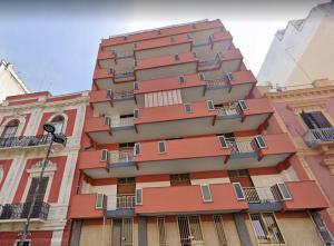 un edificio alto de color naranja con balcones a un lado. en Vimini Corso Cavour - City Center, en Bari