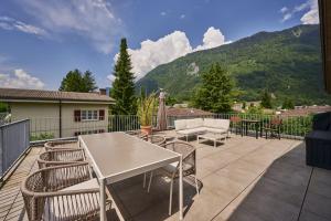 a patio with a white table and chairs and mountains at Terrace Vista Interlaken in Interlaken