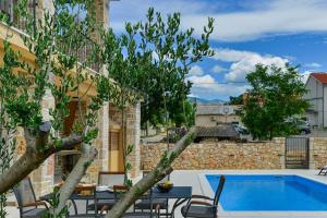 una piscina con mesa y sillas junto a un edificio en Luxury Stone Villa BANOVI with heated pool, en Vinjerac