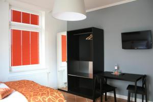 Apartmenthaus Unterwegs في روستوك: غرفة نوم بسرير ومكتب مع تلفزيون