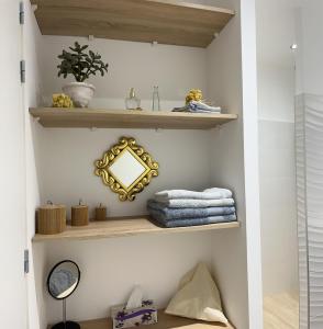 łazienka z drewnianymi półkami, lustrem i ręcznikami w obiekcie Mazet de la Lavande w mieście Uzès