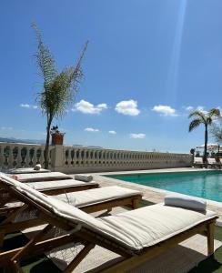 a row of chaise lounges next to a swimming pool at Hôtel Miramar in Vence