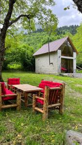 a wooden table with red chairs sitting in the grass at Iano in Oni