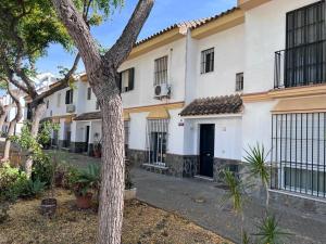 Un edificio blanco con un árbol delante. en Casa de Fernando, en Puerto Real