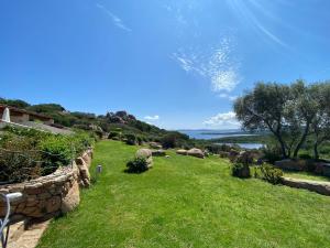 un patio con una pared de piedra y un campo de hierba en Villa Erica a Valle Dell Erica, en Valle Dell’Erica