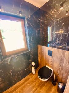 a bathroom with a black toilet with a window at Domki Widokowelove in Gliczarów