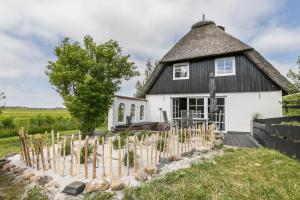 a white house with a black roof and a fence at Loft32 in Nordstrand