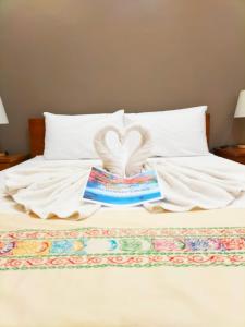 Una cama con un libro y dos cisnes formando un corazón en Dachannry's Place Hotel en Cagayán de Oro