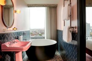 a bathroom with a pink sink and a tub and a window at The Hoxton, Brussels in Brussels