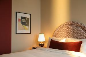 a bedroom with a bed and a lamp and a picture at The Hoxton, Brussels in Brussels