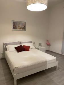 a bedroom with a bed with white sheets and red pillows at Rondi-Home in Empoli