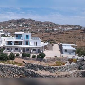 a large white house with a hill in the background at Oniropetra Apartments Mykonos in Plintri