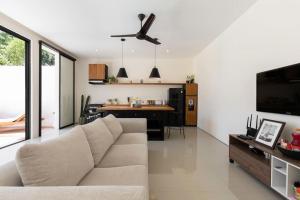 a living room with a white couch and a kitchen at The R Villa Kaba - incl. Motorbikes in Seminyak