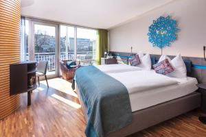 a hotel room with a large bed and a balcony at Sedartis Swiss Quality Hotel in Thalwil