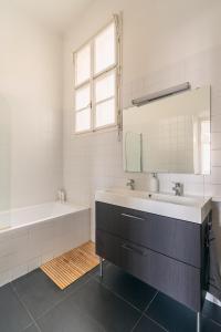 La salle de bains est pourvue d'un lavabo, d'une baignoire et d'un miroir. dans l'établissement Sunny, Airy, Artsy & Authentic Loft with Balcony, à Budapest