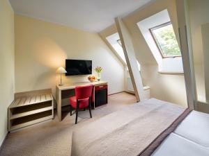 um quarto com uma cama, uma secretária e uma televisão em Hotel Michael em Praga