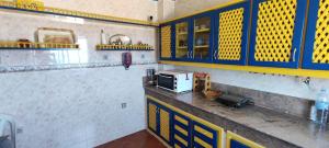 a kitchen with blue and yellow cabinets and a microwave at Appartement face à la Mer in Mrarech