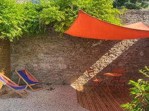 un grupo de sillas y una sombrilla en un patio en Gite à la campagne à Dijon avec jardin, en Velars-sur-Ouche