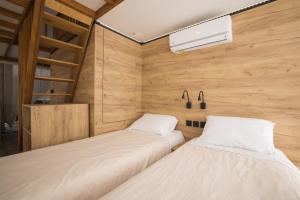 two beds in a room with wooden walls at Le lodge de la Catouniere in Castillon-du-Gard