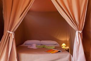 a bed in a tent with curtains around it at Le Village Vacances de Mimizan Plage in Mimizan-Plage +37 photos