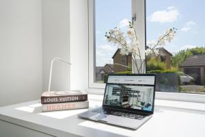 a laptop computer sitting on a desk next to a window at Detached House - Close to City Centre - Free Parking, Fast Wifi, Private Garden and Smart TV with Netflix by Yoko Property in Milton Keynes