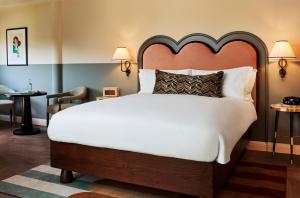 a bedroom with a large white bed with a large headboard at The Hoxton, Charlottenburg in Berlin