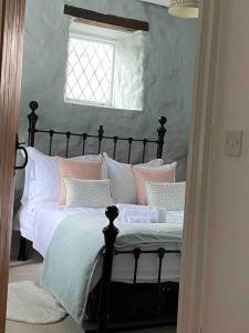 a bedroom with a bed with pink and white pillows at Luxury Cottage in Somerset in Wiveliscombe