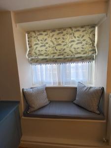asiento junto a la ventana con 2 almohadas frente a una ventana en Luxury Cottage in Somerset en Wiveliscombe