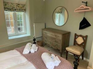 Luxury Cottage in Somerset في Wiveliscombe: غرفة نوم بسرير مع مناشف ومرآة