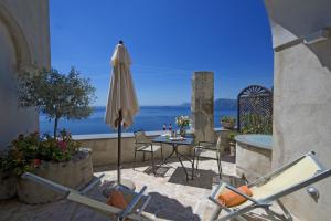 a patio with a table and an umbrella and chairs at Villa Il Frantoio and Lilmar in Praiano