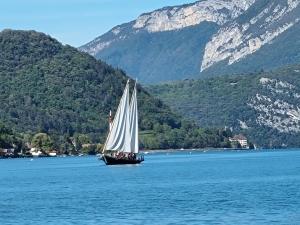 a sailboat on a large body of water with mountains at Gîte Annecy 06 - Au Royaume des Marmottes - Appt 06 in Doussard