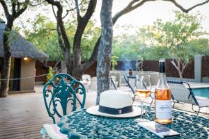 una botella de vino y un sombrero en una mesa en Nkanyi Wildlife House & Cottage, en Hoedspruit