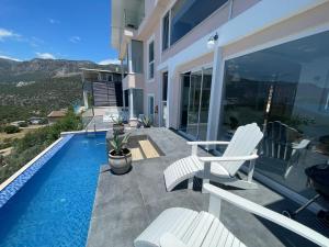 un patio con 2 sillas blancas y una piscina en VİLLA ÇAPA, en Kas