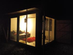 um quarto com um sofá visto através de uma porta de vidro em Abri de jardin aménagé, chambre Camping Glamour em Lalaye